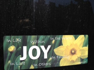 Joy bumper sticker on a dirty car