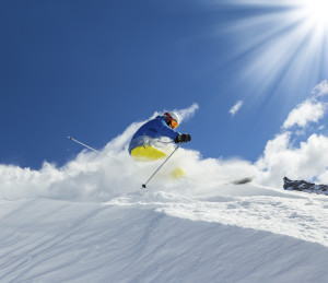 Male skier on downhill freeride with sun and mountain view