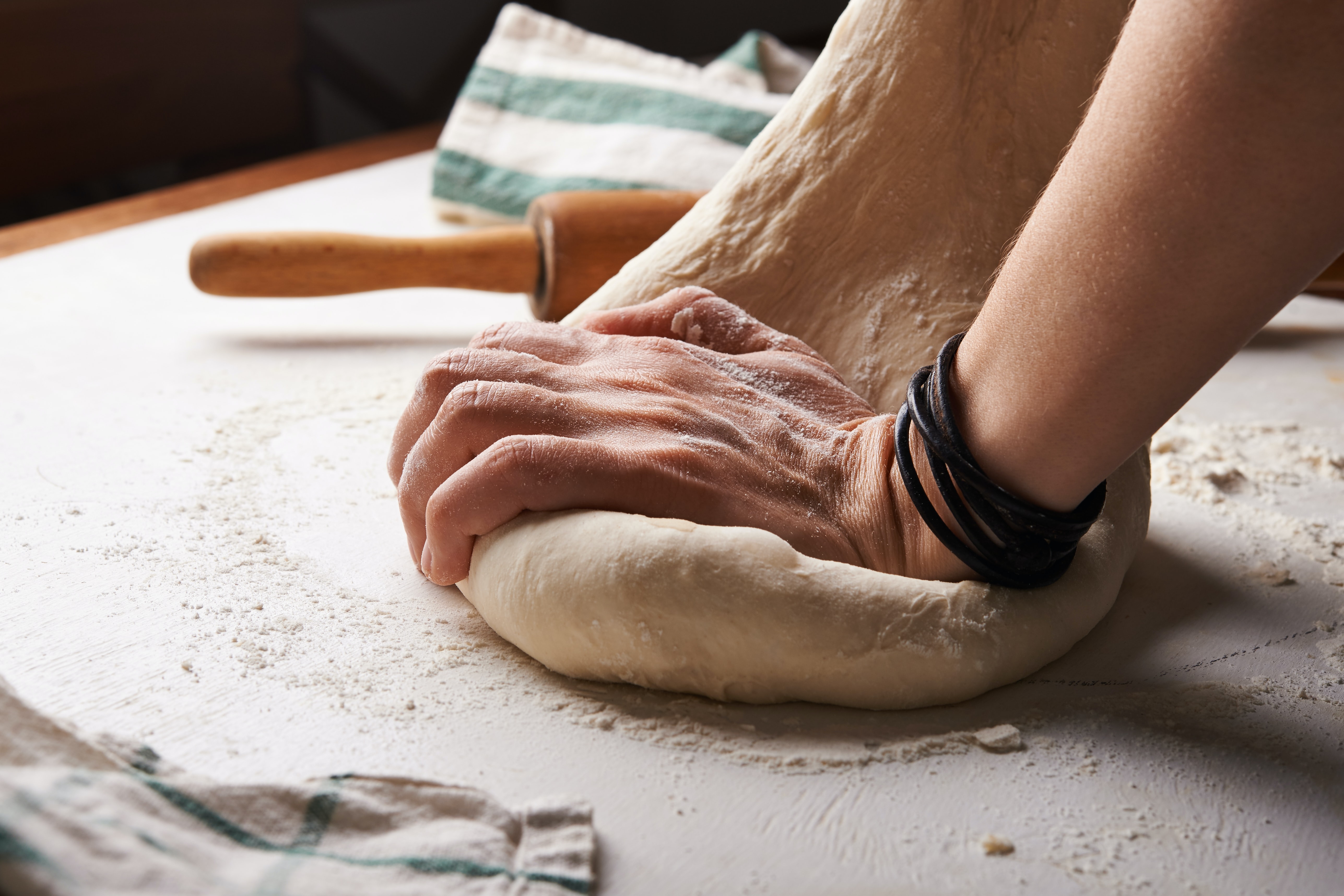 man hands kneading dough on a table