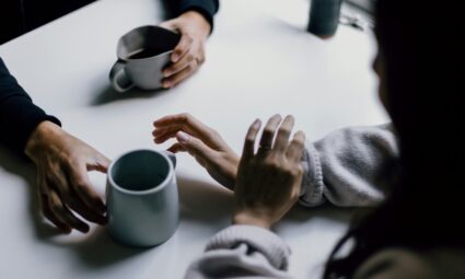 several hands holding coffee cups in a meeting