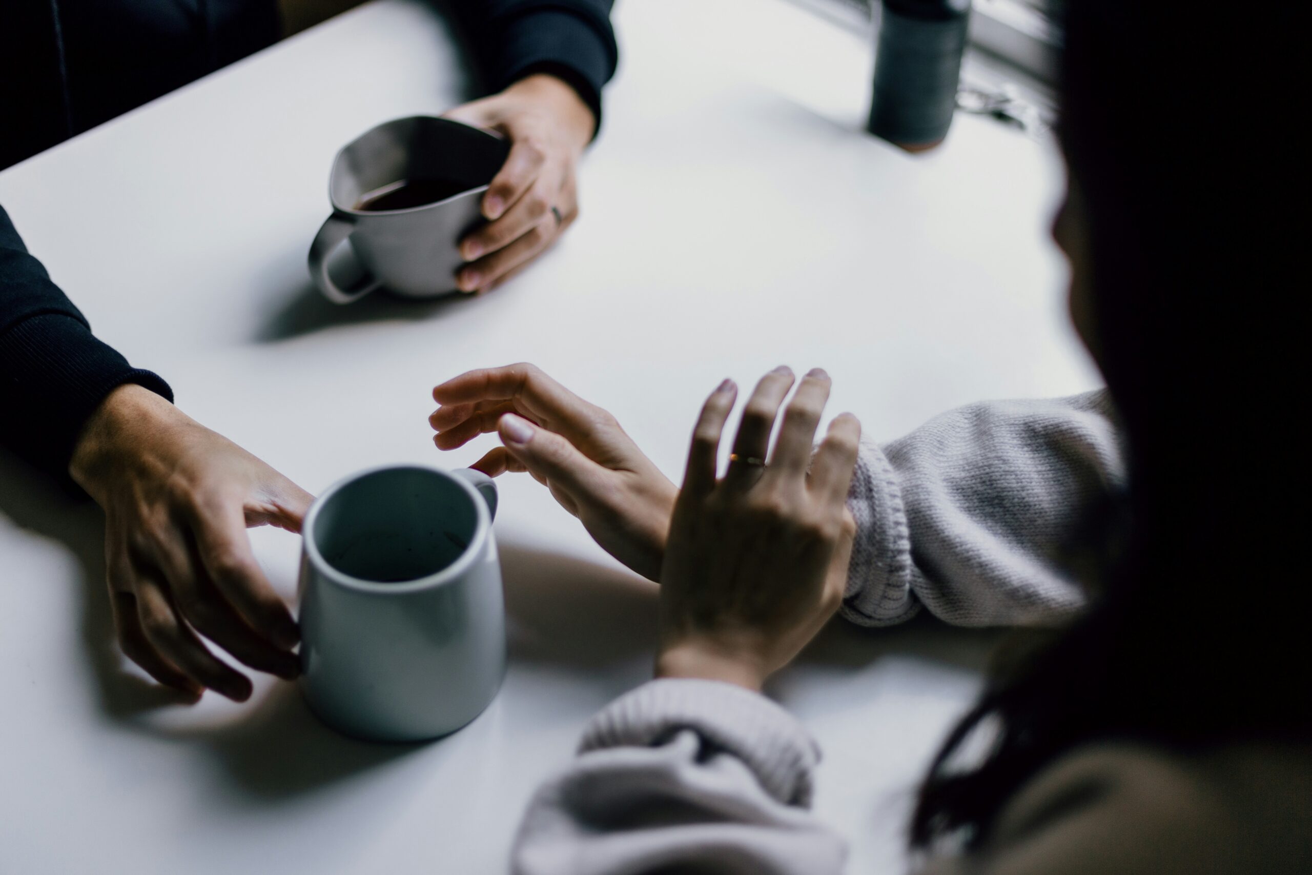several hands holding coffee cups in a meeting